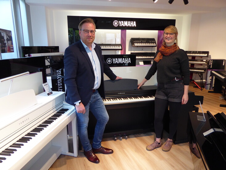 zwei Menschen stehen an einem e-piano von yamaha